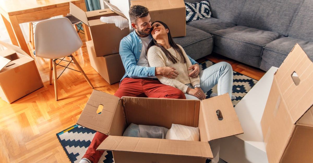 Couple embracing in new home with unpacked boxes
